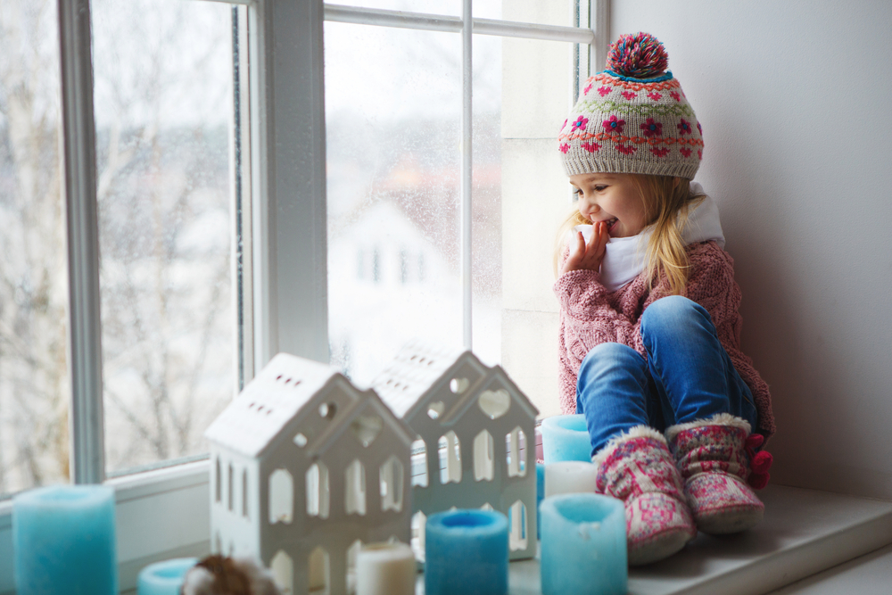 a little girl looking out a window during the winter time